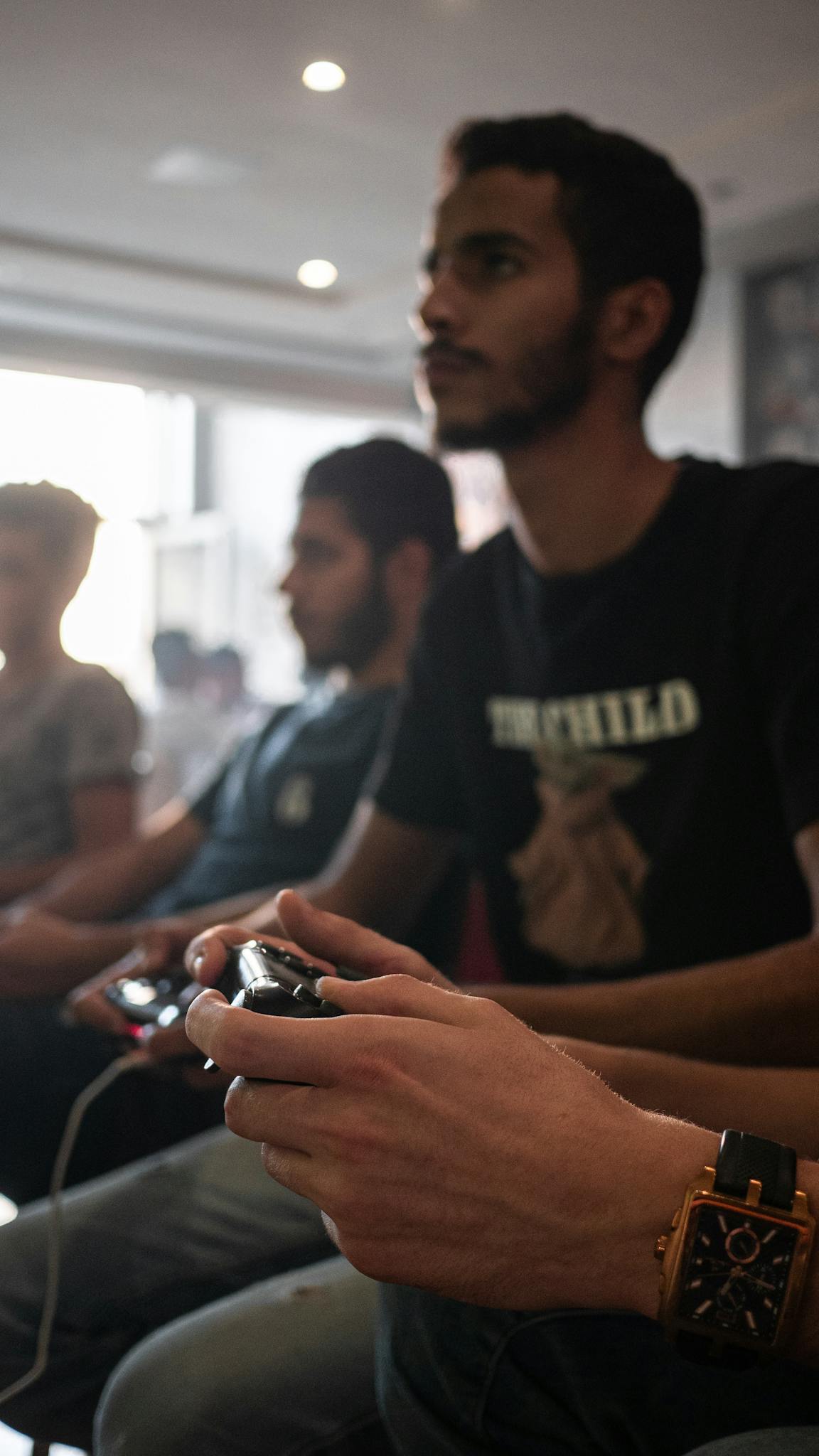 Young men intensely focused on gaming indoors, enjoying a competitive session.